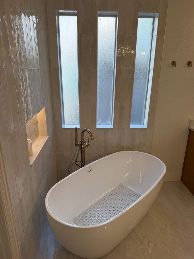 Freestanding tub under tall windows with lit niche