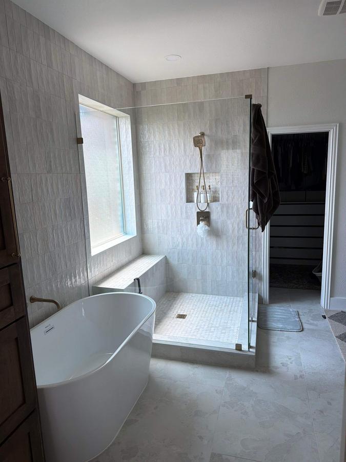 Freestanding tub beside glass shower in primary bath